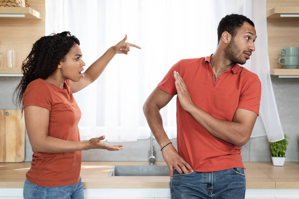 Upset angry millennial african american wife screaming scolding offended husband in kitchen interior. Breakup, conflict, human emotions, relationship problems, stress and scandal at home due covid-19 - Fotoğraf, Görsel