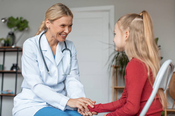 Pretty schoolgirl having appointment with friendly professional female pediatrician at modern clinic, copy space. Modern healthcare for children concept - Photo, Image