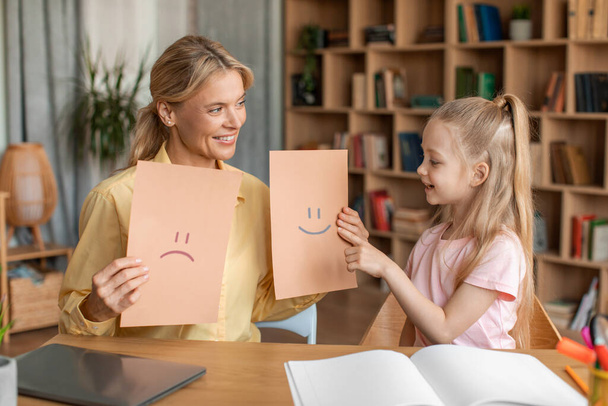 Friendly female teacher and little girl preschooler exercising at daycare, learning about emotions, having private lesson at home. Child development, emotional intelligence for kids concept - Photo, Image