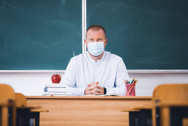 Teacher with mask in the classroom. Social distanting and classroom safety during coronavirus epidemic - Фото, изображение