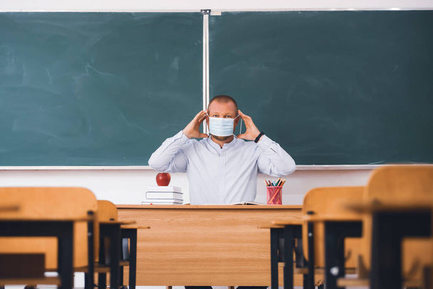 Teacher with mask in the classroom. Social distanting and classroom safety during coronavirus epidemic - Fotó, kép