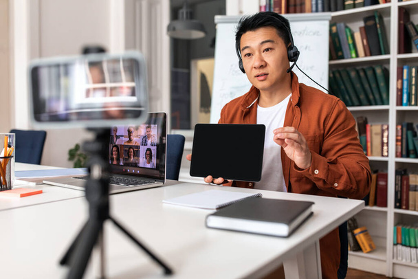 Online Teaching And Learning. Asian Teacher Man Showing Digital Tablet To Laptop And Smartphone Teaching Having Video Conference Lecture Sitting In Modern Classroom. Selective Focus - Foto, imagen