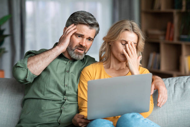 Infidelity Concept. Depressed wife catch husbands correspondence with another woman on laptop, middle aged lady found out about her partners love affair, stressed man looking at computer screen - Valokuva, kuva