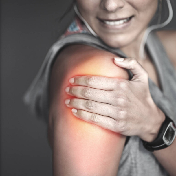 Вибачте після важкого тренування. молода жінка тримає поранене плече, що виділяється червоним
 - Фото, зображення