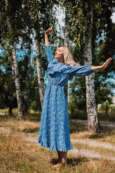 A woman with bare feet. Rustic style. Birch grove in the background. Beautiful blonde - Φωτογραφία, εικόνα