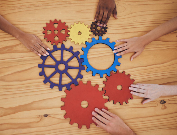 Hands, gears and collaboration with a team of people working with cogs and equipment on a table in the office. Teamwork, synergy and planning with a business group meeting to talk company strategy. - Foto, afbeelding