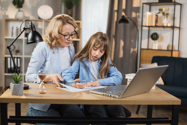 Young caucasian mother helping daughter remote studying at home explaining doing homework together. Parent mom teaching teenage school child distance learning online virtual class on computer. - Φωτογραφία, εικόνα