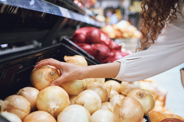 Vegetables, grocery shopping and health while a customer choose fresh onions in supermarket or greengrocer store. Close up hands of woman buying vegan food groceries before inflation at retail market. - Foto, afbeelding