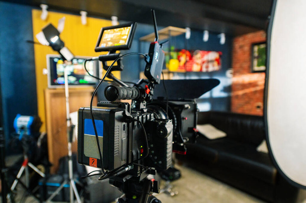 A professional camera on a tripod at a film set, interior on the background - Fotó, kép