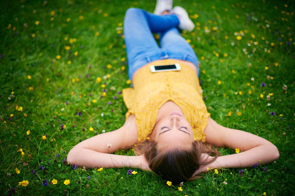 Simple pleasurestheyre priceless treasures. a young woman lying down in a field of grass - Fotoğraf, Görsel