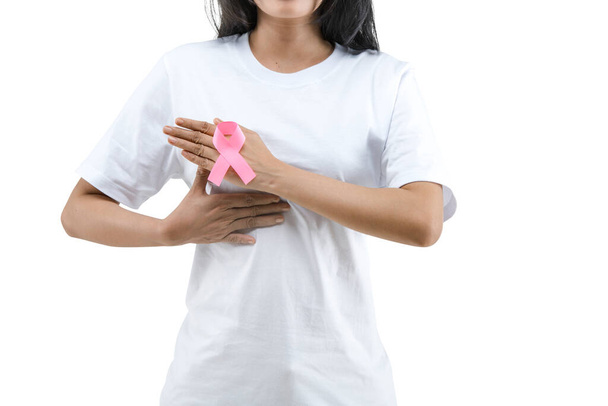 A woman in a white shirt shows a pink awareness ribbon isolated over white background. Breast cancer awareness - Fotoğraf, Görsel