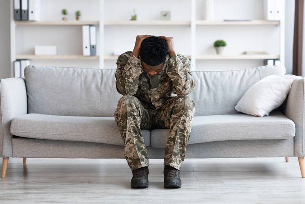 Stressed african american young man soldier in military uniform sitting on couch at psychotherapist office, covering his head and crying, having mental health issues, full length shot, copy space - Photo, image