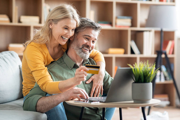 Beautiful Middle Aged Couple Making Order From Internet With Laptop And Credit Card, Happy Mature Spouses Doing Online Shopping Or Virtual Payments While Relaxing With Computer At Home, Free Space - Fotó, kép