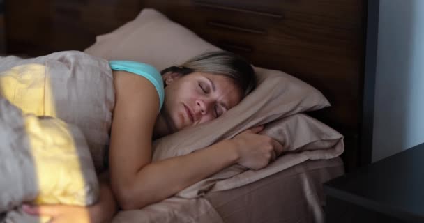 Bright sunlight wakes up young woman in bed. Positive morning awakening concept - Video