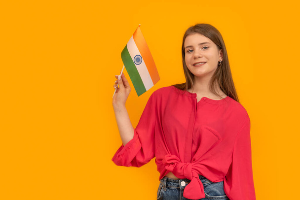 Beautiful young girl of European appearance with the flag of India on orange background. Travel to India - Fotó, kép