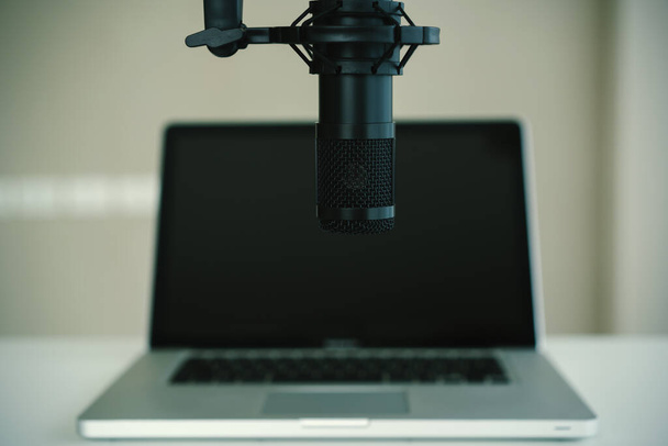 Home sound recording studio and equipment including professional condenser microphone, headphones, and laptop computer for audio mixing. Digital audio sound recording studio at home. - Photo, image