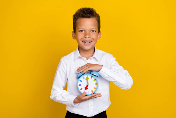 Portrait of positive person hands hold classic bell clock toothy smile isolated on yellow color background. - Photo, Image