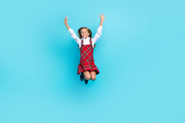 Full size photo of carefree energetic person jumping have fun raise arms isolated on blue color background. - Foto, Imagen