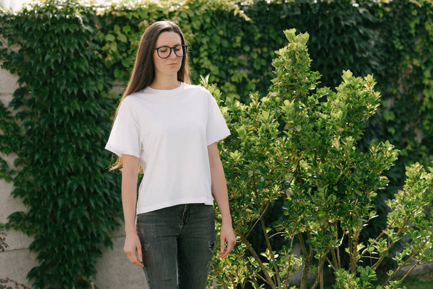 Woman wearing white t-shirt with space for logo or design in the park in summer - Foto, Bild