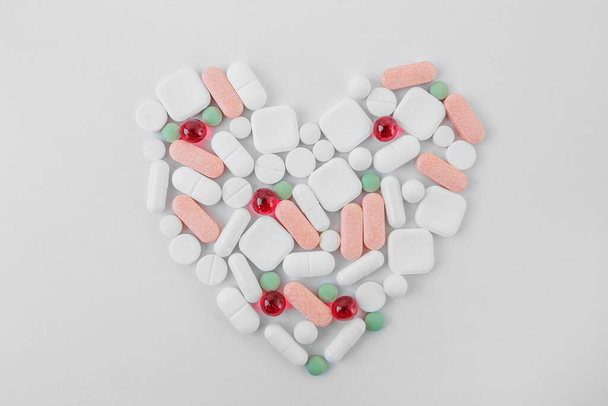 Many different pills on white background, laid out in form of heart. Copy space. Top view. Concept of pharmaceuticals, medicine and healthcare - Foto, immagini