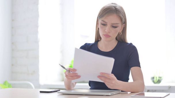 Young Woman Reading Reports while Sitting in Office - Photo, Image