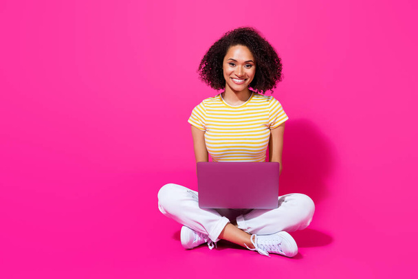 Full length photo of young attractive girl sitting use computer smile positive empty space new programmer ad isolated on pink color background. - Foto, imagen