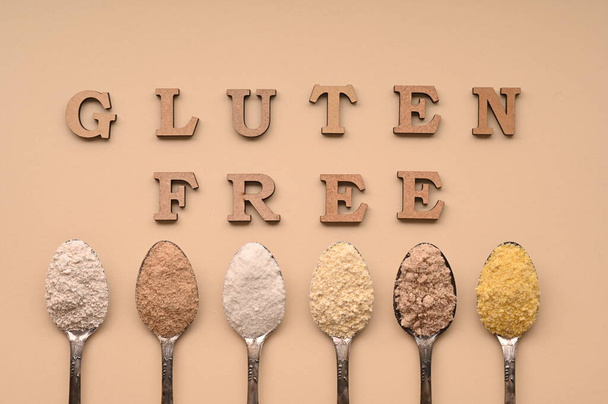 Gluten free text and spoons of various gluten free flour, almond buckwheat, rice, corn, oat, chickpea. Flat lay, top. - Foto, Imagen