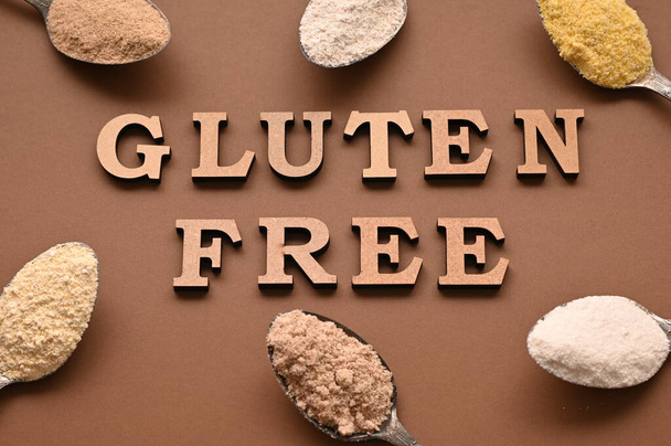Gluten free text and spoons of various gluten free flour, almond buckwheat, rice, corn, oat, chickpea. Flat lay, top. - Photo, image