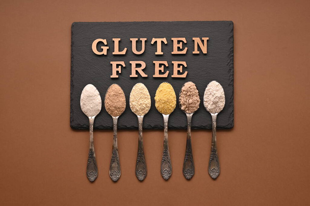 Gluten free text and spoons of various gluten free flour. Flat lay, top. - Fotó, kép
