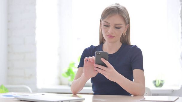 Młoda kobieta za pomocą smartfona w biurze - Zdjęcie, obraz