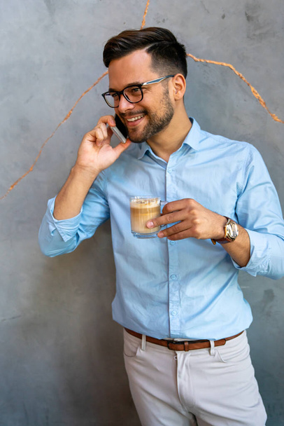 Portrait of successful business man talking on smartphone in coffee break in corporate office - Foto, Bild
