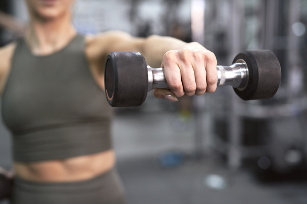 Close up of dumbbell held by unrecognizable sportsperson at the gym - Фото, изображение