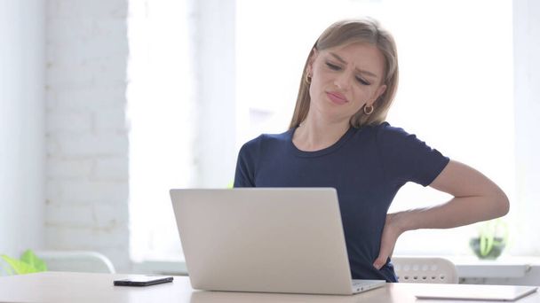 Young Woman having Back Pain while using Laptop - Foto, afbeelding