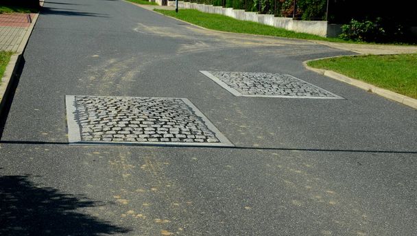 in the middle of the road leading to the residential area, the police and the traffic office installed cobblestone retarder. raised square made of rubber beveled on sides, bumpy, two, paving - Foto, Bild