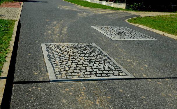 in the middle of the road leading to the residential area, the police and the traffic office installed cobblestone retarder. raised square made of rubber beveled on sides, bumpy, two, paving - Fotografie, Obrázek
