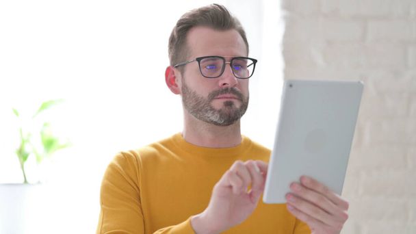 Atractivo hombre de mediana edad usando tableta en la oficina - Foto, imagen