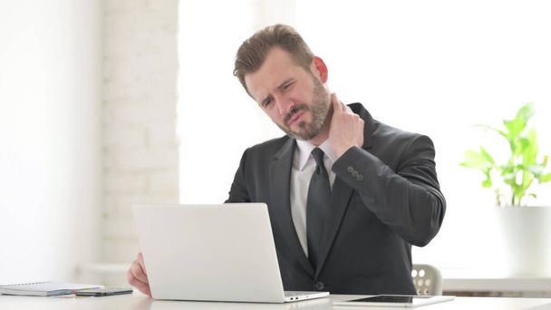 オフィスでラップトップを使用している間に首の痛みを持つビジネスマン - 写真・画像