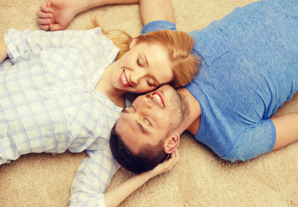 smiling happy couple lying on floor at home - Fotografie, Obrázek