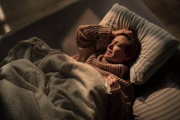 Сумна жінка, яка страждає депресією, лежить в ліжку вночі
. - Фото, зображення