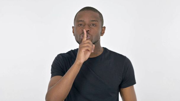 Silencio por favor, hombre africano con dedo en los labios sobre fondo blanco - Foto, imagen