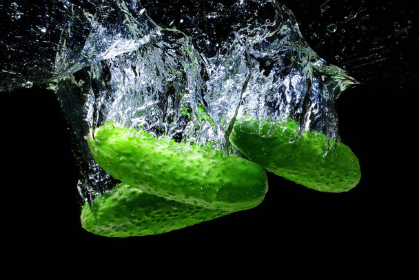 Fresh cucumbers falling underwater with splashes isolated on black background. - Fotoğraf, Görsel