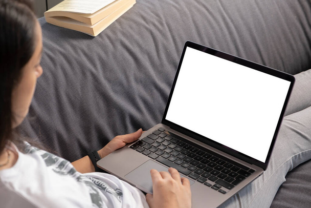 Moderne laptop, vrouw met een moderne laptop. Wit blanco computer notebook scherm voor mock up. Blank jong meisje ontspannen op de bank. Film kijken, online vergadering bijwonen, op afstand werken - Foto, afbeelding