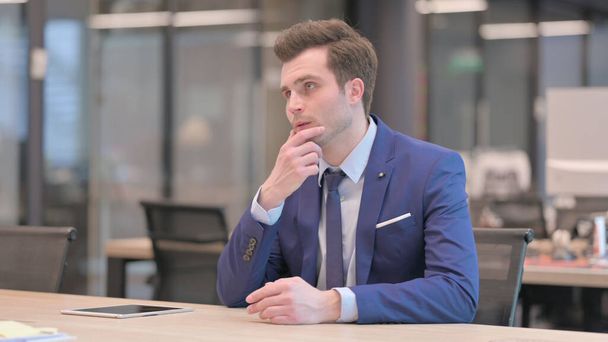 Töprengő középkorú üzletember gondolkodás közben ül a hivatalban - Fotó, kép