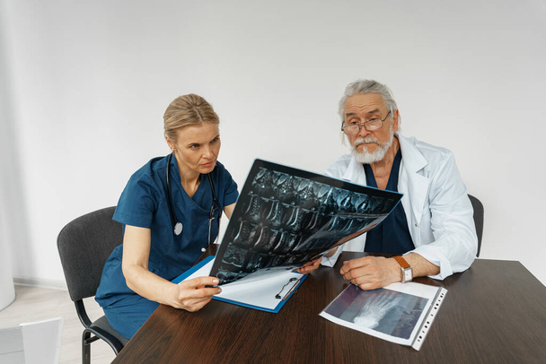 Team of doctors looking on results of X-Ray or MRI scan of patients spine in medicine office - Fotoğraf, Görsel
