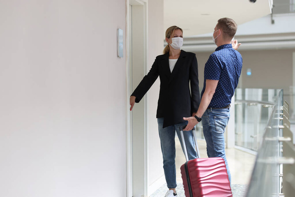Two tourists observe sanitary rules during pandemic and check into room in hotel room. Travel health safety concept - Photo, image