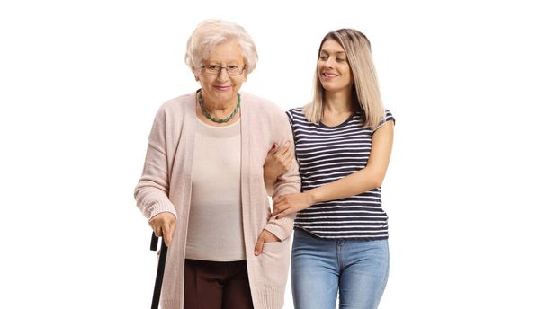 Young woman helping an elderly woman walking with a cane isolated on white background - Фото, зображення
