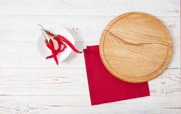 Holztisch, rote Serviette, roter Pfeffer auf dem Tisch.Tischdecke Urlaubskonzept - Foto, Bild