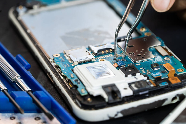 Technicien réparer l'intérieur du téléphone portable par le fer à souder. Circuit intégré. le concept de données, de matériel, de technologie. - Photo, image