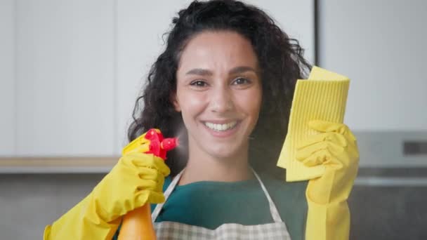 Happy young housewife mistress female maid worker housekeeper mother wife posing in kitchen wears yellow rubber protective gloves hold cleanser bottle spray detergent liquid on wet rag for cleaning - Séquence, vidéo
