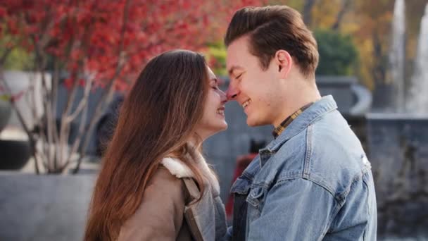 Gentle caucasian boyfriend man caress loved girlfriend woman talk about future outdoors stand closeness rub noses touch each other on romantic date couple partners young lovers cuddle in autumn park - Video